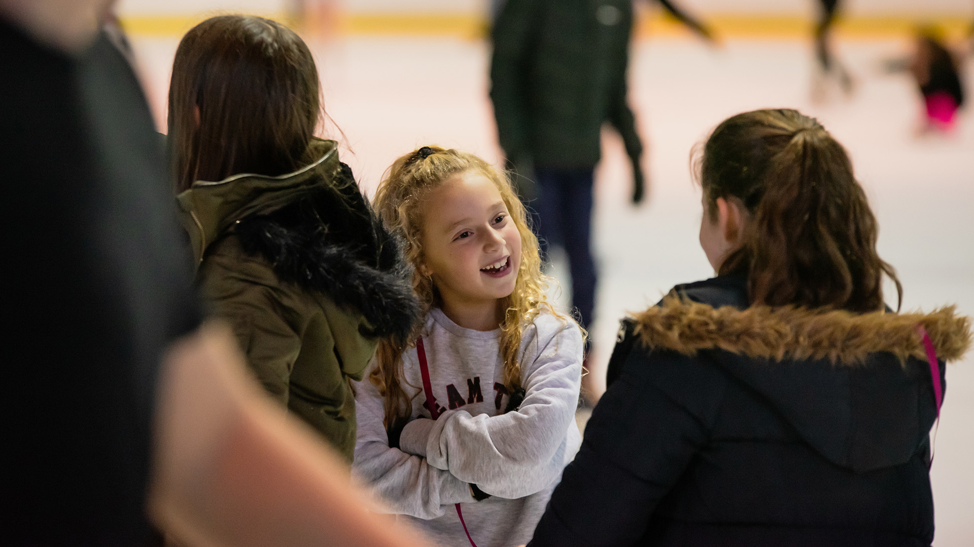 Young girls chatting and ice skating.