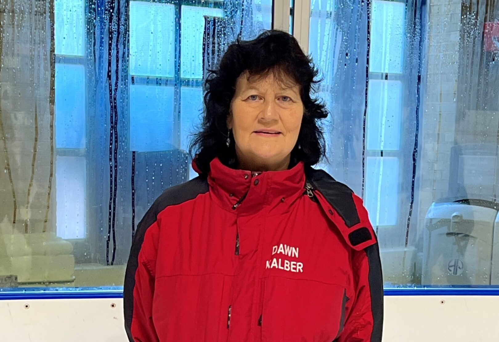 Woman with dark hair and red coat looking at camera