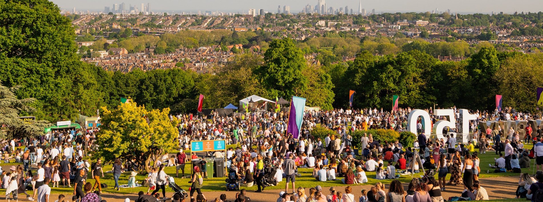 Large group of people in a field enjoying a festival on a sunny day.